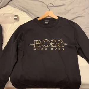 HUGO BOSS med guld text storlek S - Äkta Hugo boss tröja storlek S svart med guld text, köpt på zalando kvitto finns på zalando. Säljer för att den är för liten. Skick 10/10.