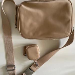 En axelremsväska  - En beige axelremsväska med bra skick och en liten väska vid axelbandet (pris kan diskuteras)