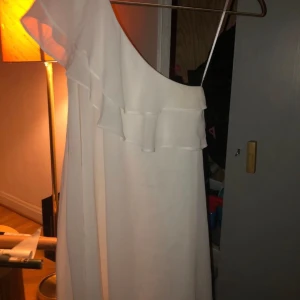 Enkel fin klänning! - Jättefin och söt klänning, endast använd en gång 🤍 Den är enaxlad med dubbelvolang, köpt på Nelly och är i strö XS