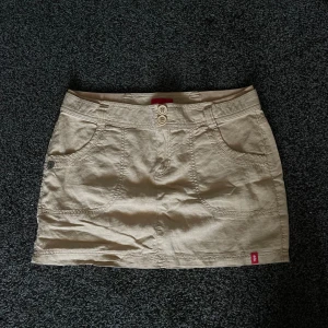 beige kjol - jättesöt lågmidjad beigekjol med en jättefin design på baksidan! från märket edc  midja: 39cm rakt av längd: 34cm 