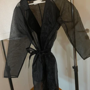 NELLY genomskinlig kappa  - En genomskinlig kappa med band, från NELLY. Inte används mer än 1 gång. I bra skick.  Storlek 36 dock känns som en 38:a.   