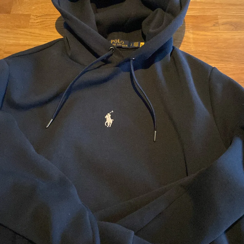 Ralph lauren hoodie, marinblå  Köpt och nypris för 1999kr Använd ett fåtal gånger.  Finns inget fel på den, de ända är att i sidan vid midjan har den blivit nopprig men syns knappt. För mer frågor kontakta gärna.  *Pris går att diskutera*. Tröjor & Koftor.