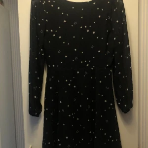 Klänning - Svart klänning med vita stjärnor som har V-ringning i ryggen. Klänningen är från Cubus i barnstorlek 164, men passar även xs och kan passa s. Bra skick!😊✨
