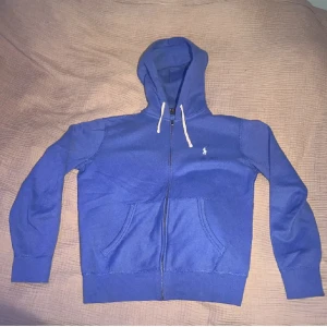 Polo Ralph Lauren Zip Hoodie - Säljer nu denna blåa Polo Ralph Lauren Zip Hoodie i utmärkt skick. Den är u storlek S. Tveka inte på att skicka ett meddelande vid funderingar. Mvh