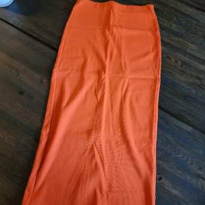 En lång kjol med slits i en härlig orange färg. Enbart använd en gång.