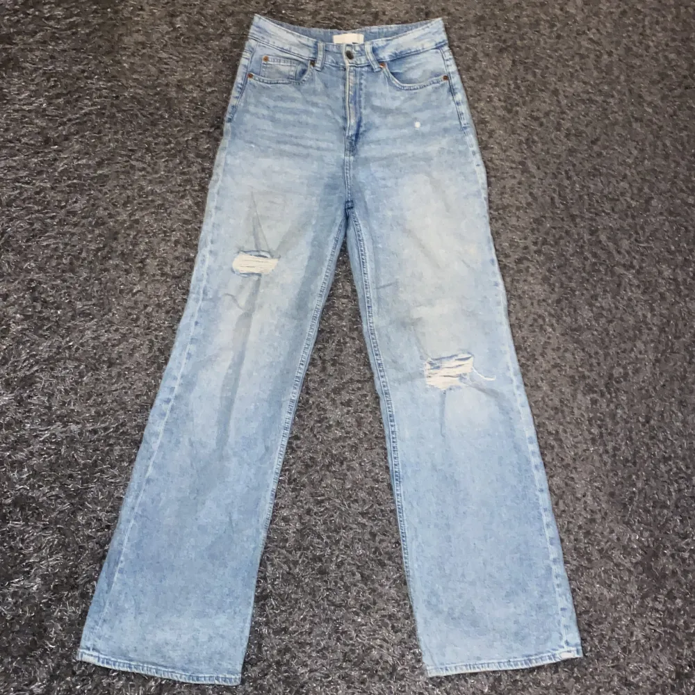 Ljusblå jeans med vida ben och slitningar på benen i storlek 36. . Jeans & Byxor.