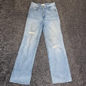 Vida jeans - Ljusblå jeans med vida ben och slitningar på benen i storlek 36. 