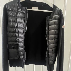 Moncler cardigan - Säljer denna fina Moncler cardigan, köptes på plick men var tyvärr för liten! Inget kvitto men går att scanna qr kod osv. Som ny MEN det finns en defekt vid nackkragen (bild 4) som är ett hål men går lätt att sy ihop. Skriv vid intresse!🤍