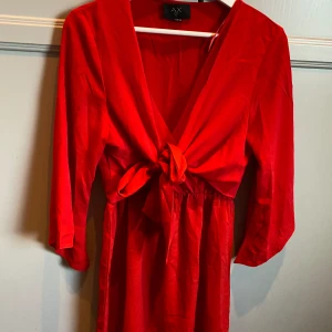 Röd klänning  - Röd klänning från AX PARIS  Helt ny- aldrig använd  Rosett som man kan knyta som man vill! Storlek 40/M  Nypris 599kr Rök och djurfritt hem! 