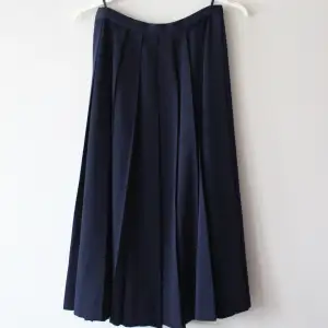 Marinblå/mörkblå kjol plisserad. Inget märke eller storlek men skulle säga att den är runt S. Midja (tvärs över): 32 x 2 Längd: 73 cm. 
