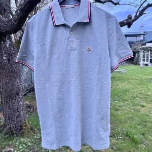 Moncler Piké - Säljer min helt nya grå Moncler piké. Helt ny med lappar och påse. Har endast provat den. NFC Scan på loggan och alla lappar. Storlek L men sitter mindre så passar M/L. Perfekt till sommaren. Har fler bilder, på lapparna. Skriv vid frågor!💫