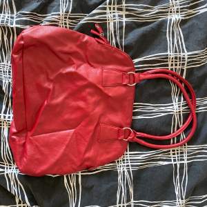 Röd väska från ett märke som heter Daniel Hechter. Bra skick. 