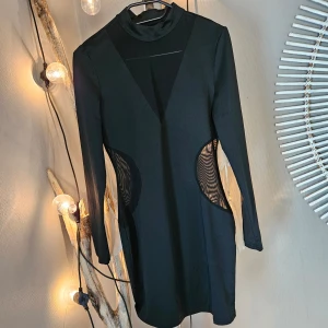 Klänning - Svart klänning med genomskinligt tyg vid sidorna och bröstet. Aldrig använd. 