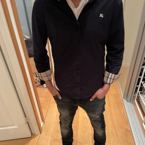 Burberry skjorta  - En mörkblå brunett skjorta i storlek xl i barn men passar folk i storlek S. nypris ligger på ca 4-5 tusen jag säljer för endast 1349 skick 10/10