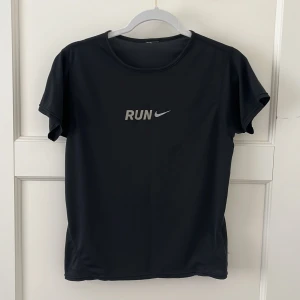 Nike RUN t-shirt - Svart Nike t-shirt för träning med texten RUN i reflex. Denna kan du springa snabbt i! Väldigt tunnt och behagligt material och i storlek som passar XS och S skulle jag säga. 