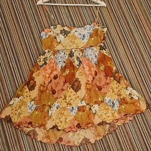 Sommarklänning  - Utslängd klänning som är tajtare vid brösten. Den har en dragkedja på sidan av kläningen och öppen rygg.