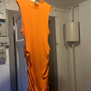 Orange klänning - Säljer nu min fina, väldigt orangea klänning från H&M. Den är i ett tunt material, därmed lite genomskinlig. På sidorna är den lite ihopdragen (se bild) men finns snören man kan dra i och ändra💕 Den slutar typ på mitten av låren☺️