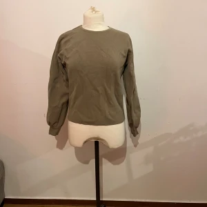 fin khakigröntröja - fin och skön khakifärgad tröja från & other stories, använd vid två tillfällen. lite skrynklig då den legat i garderoben, men går lätt att stryka🌷