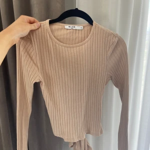 Tröja - Beige ribbad tröja med knyte i ryggen. Oanvänd 
