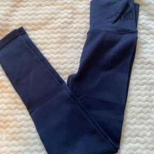 Rib seamless tights - Ribbade tights från Stronger i nyskick. Färgen är lite  mer dämpad än vad som syns på första bilden. Säljer även matchande crop top. Nypris: 699kr