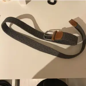 Ett eftertraktat bälte i färgen grå, bältet är 100cm. 