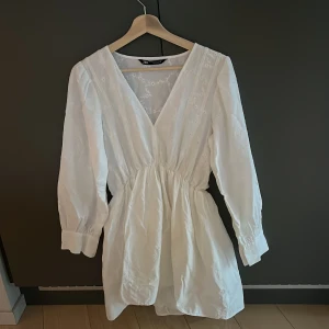 Studentklänning med brodyr  - Superfin vit klänning från Zara med söt blombrodyr. Den här långa lite puffiga ärmar och fin ringning vid halsen. Använd sparsamt så den är nästan i nyskick. 