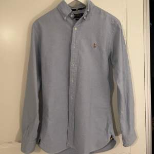 En ljusblå Ralph Lauren skjorta i mycket fint skick.  Har knappt kommit till användning då den är lite för liten för mig    Storlek Small 
