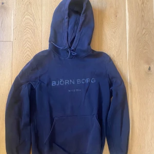 Björn Borg hoodie - Tröjan ser blå ut på bilden men är mer marinblå/svart Inte nopprig och ser inga tecken på användning 