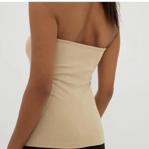 Bandå topp - En rosa/beige bandå topp. Köpt från NA-KD för 3 månader sen. Jag köpte den för 199kr. Den har storleken S men passar även mig som är M. Använd 1gång för en fest. Inga defekter