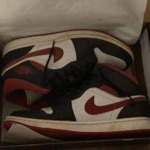 Air Jordan 1 mid white/gym red-black - Säljer dessa skor för att jag har vuxit ur dom, dom är väldigt snygga, men dock lite smutsiga.Dom är storlek 41.