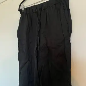 Ett par svarta linne byxor från H&M, med resår i midjan och ett knyte.  I stl S. 