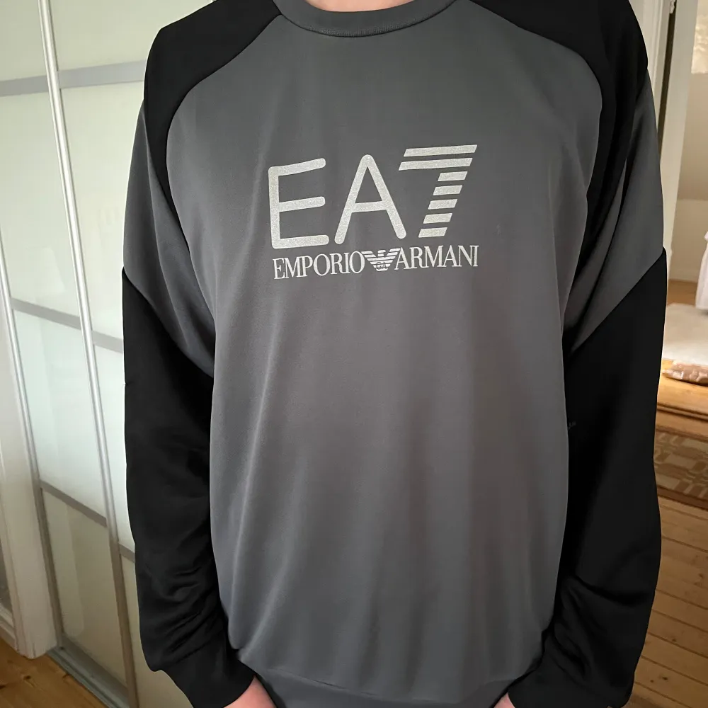 Långärmad EA7 tröja i färgen grå och svart. Nypris 1000kr. Väldigt bra skick och har aldrig blivit använd och har inga tecken på användning. Passar storleken M. Hoodies.