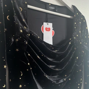 Eras tour topp💫⚡️ - Superfin blus tänkt att ha till Eras tour. Oanvänd. Svart sammetstopp med guldiga stjärnor och månar. Fyrkantig urringning ocxh utsvängda armar. Midnights tema!! Storlek L men mer som en M
