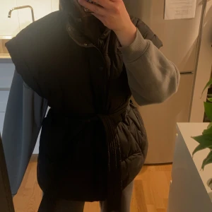 Väst - Säljer denna svarta västen från Gina tricot i storlek M som är lite oversized på mig som är S. Super skön och bekväm med midjeband. Köparen står för frakten!