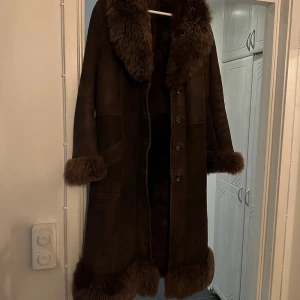 Kappa i mocka med fuskpäls - Superfin lång kappa i mocka med innerfoder av fuskpäls. Står ingen storlek men skulle uppskatta den till en L/ XL. Funkar på en M om man vill ha den oversize! 
