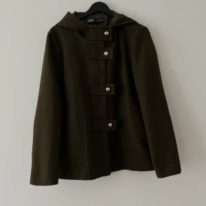 Grön jacka zara - Grön jacka från zara med guldknappar/spännen och luva. Strl L men på mig som bär xs/ s passar den bra om man gillar den lite lösare och mer oversized. Passar vår o höst o vinter