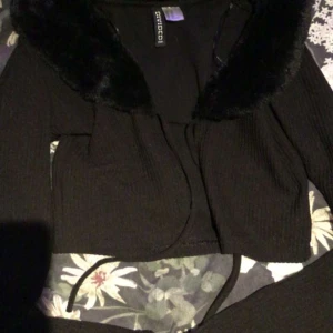 En svart tröja med päls runt halsen - Den har använts 2 gånger och är i bra skick och är inte trasig eller något