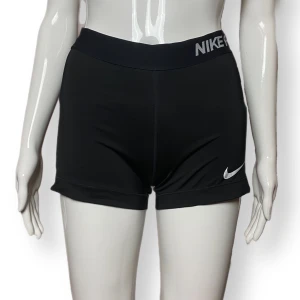 Nike träningsshorts - Storlek M, men liten i storlek? Stretchig material. Finns två hål på ena sidan - se bild tre. Nike märket har blivit lite slitet med tiden. Mått: Midjebredd 31cm, längd ca~ 25cm 
