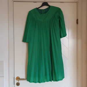 Vintage klänning  - Vitage, retro klänning. Grön.  Veckad. 3/4 ärm. Från Kiddie ateljén. Storlek 36. Från 70 talet. Dragkedja i ryggen som fungerar felfritt. Från ett rök- och djurfritt hem. Tvättad. Luktar ej tant. 