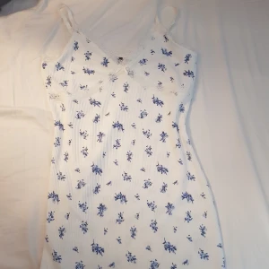 Drömmig blå blommig klänning  - En vacker ribbstickad klänning, vit med fina blå blommor🦋 Aldrig använd och har prislappen kvar!