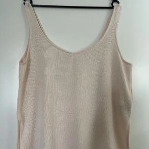 Topp H&M L - Cremevit topp från H&M i storlek L. 50% polyester och 50%viskos, tjockare material. Små snitt på sidorna. Toppen är i mycket god skick, som ny.   Mått: Längd ca 65 cm Byst ca 58 cm Midja ca 58 cm  Plagget kommer från ett djur- och rökfritt hem. Plagg