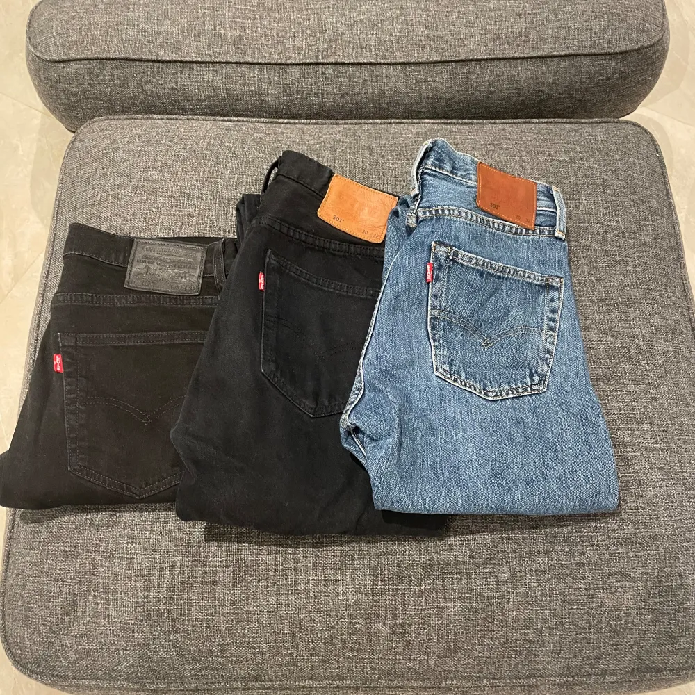 Tre par Levi's jeans, två stycken i svart och ett par i blått. Båda paren har den klassiska Levi's designen med fem fickor och en läderetikett på baksidan. Svarta byxan längst till vänster är 502 och är en annan modell.  300:- kr styck.. Jeans & Byxor.