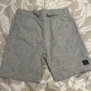 Grå shorts med dragsko - Ett par bekväma grå shorts med dragsko i midjan. Shortsen har fickor på sidorna och en bakficka.