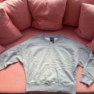 College tröja från Adidas - En grå college tröja från adidas med en snygg passform och skönt material  Storlek M men känns lite mer som S skulle jag säga - aldrig använd så i väldigt bra skick  Inga returer men jag kan mötas upp