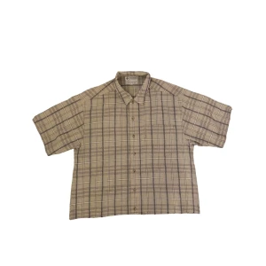 Beige rutig skjorta från Columbia - En bekväm beige rutig skjorta från Columbia Sportswear Company. Skjortan är kortärmad och tillverkad av 100% bomull, vilket gör den perfekt för varmare väder.