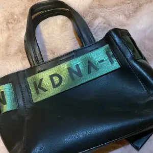 En svart NAKD väska med gröna detaljen. Aldrig använd och har inga skador. Säljer då den aldrig har kommit till användning. Det finns inte kvar i webbshoppen