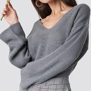 Grå Stickad Tröja - Lite croppad stickad tröja från Nakd x Dilara Özcan kollektionen. Mycket fint skick. 