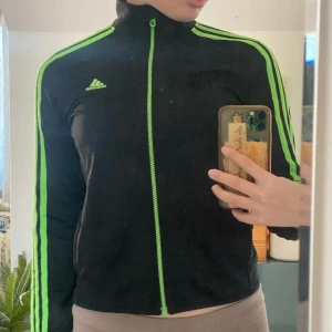 En adidas training jacket  - En grön och svart träningsjacka. Inga tydliga slitage. Är från barnavdelningen men använder den som en s. 