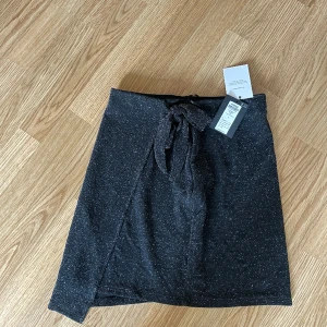 Glittrig kjol - Glittrig kjol med slits och knytning , helt oanvänd 