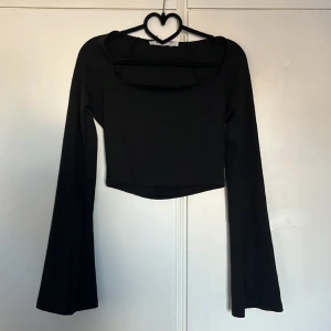 Festtopp - En svart kortare festtopp med långa ärmar från nakd.